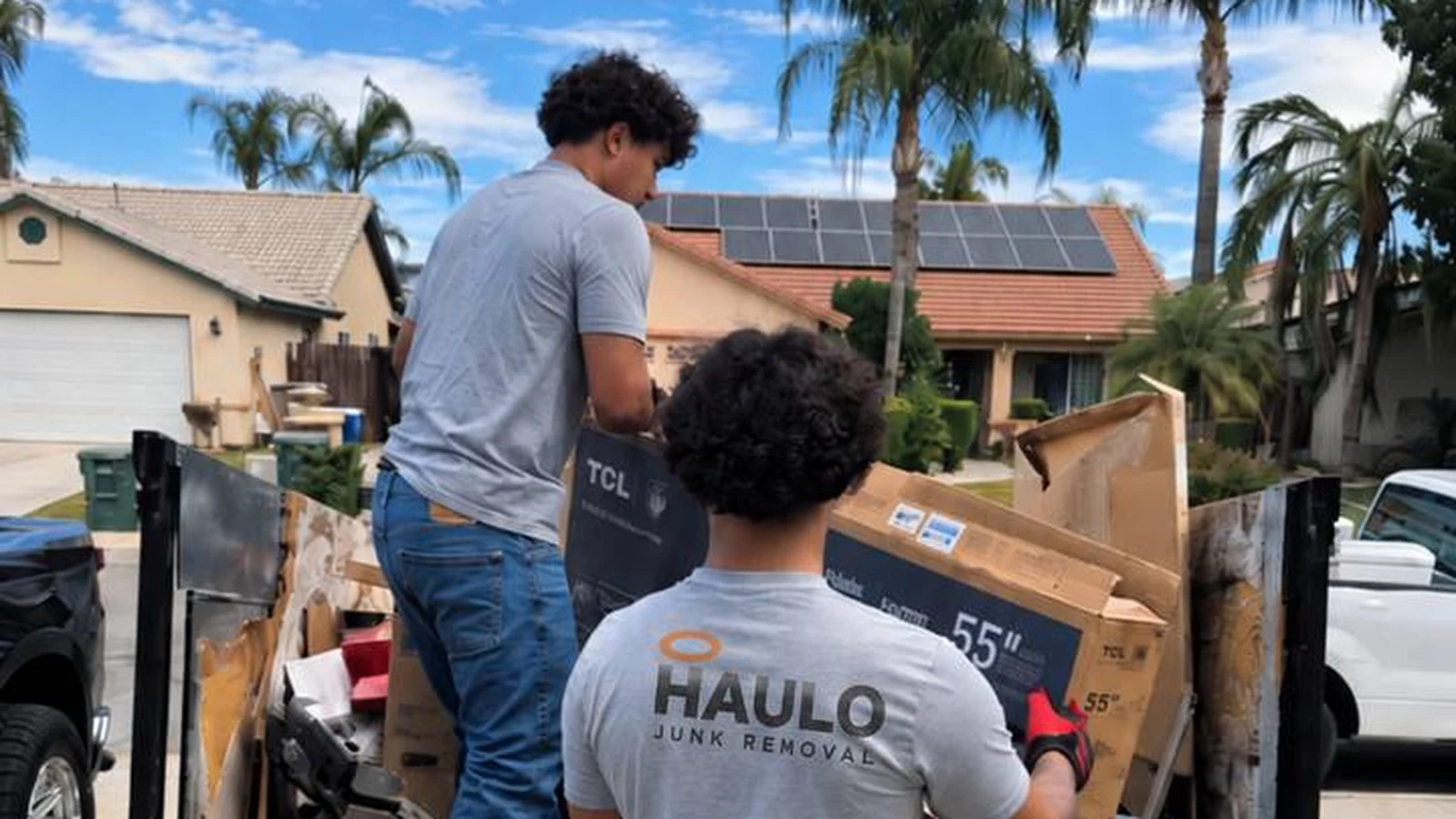 Haulo crew members loading a full junk-removal trailer in a Mesa neighborhood