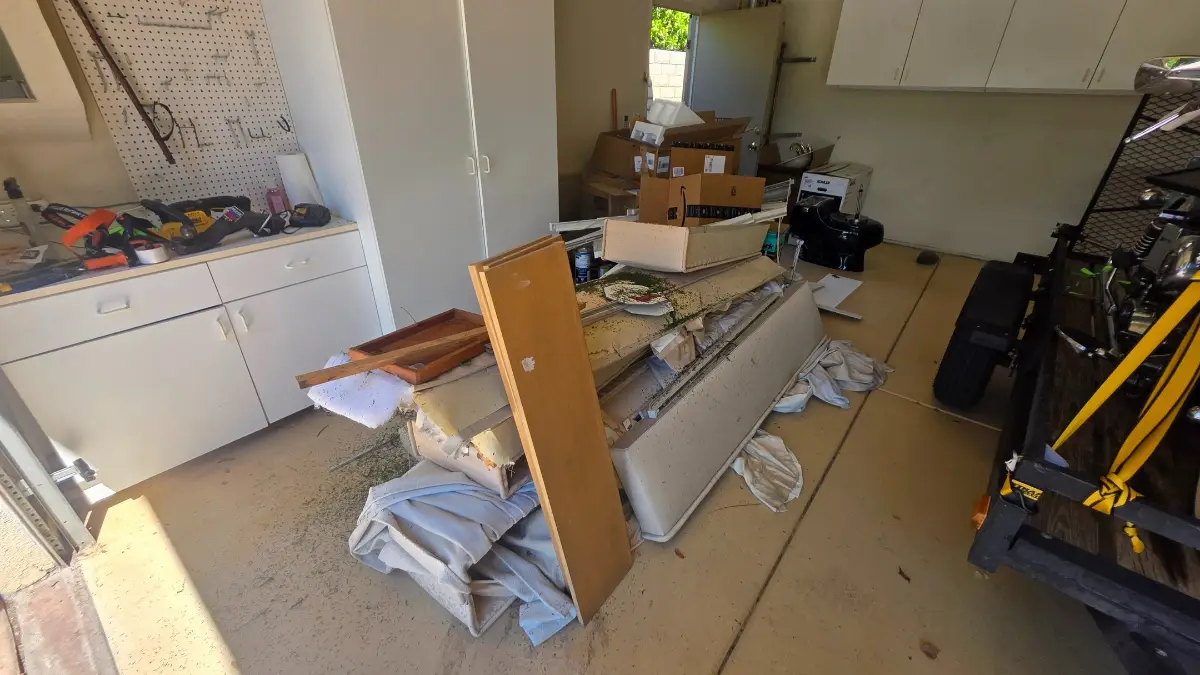 An Avondale garage with a box spring, boards, boxes, a toilet and drawers piled on the floor