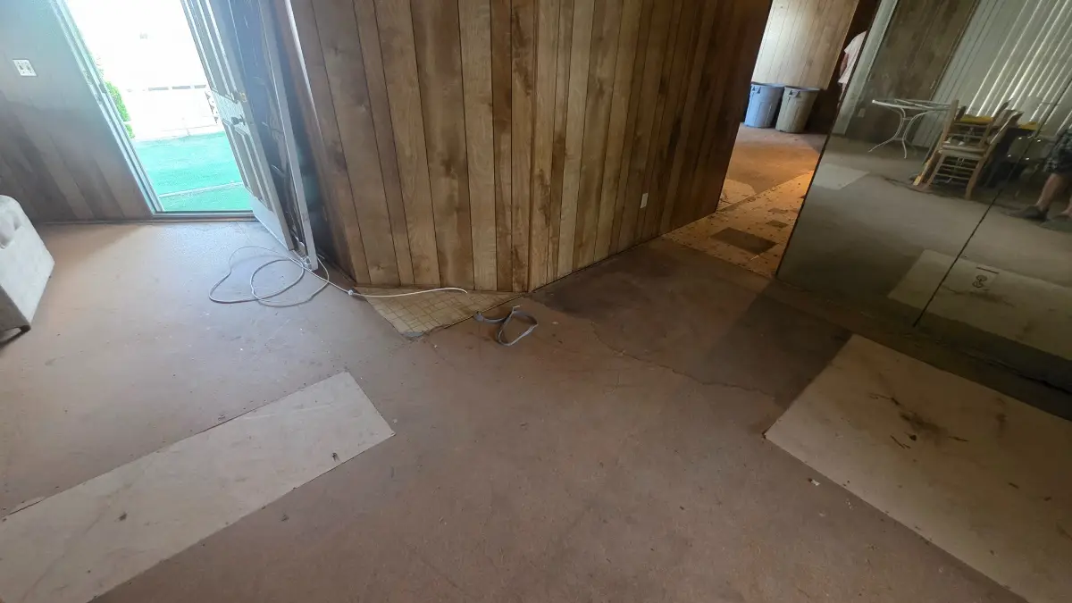 The same Chandler wood-paneled wall with the appliances gone and the subfloor clear