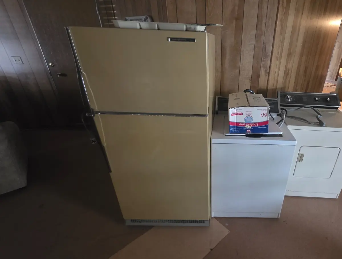 A refrigerator, a washer and a dryer against a wood-paneled wall in a Chandler mobile home