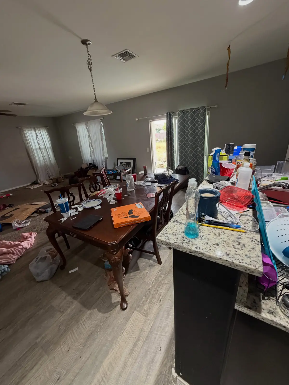 A Chandler living and dining room with a table, chairs and a bar counter covered in dishes and loose contents