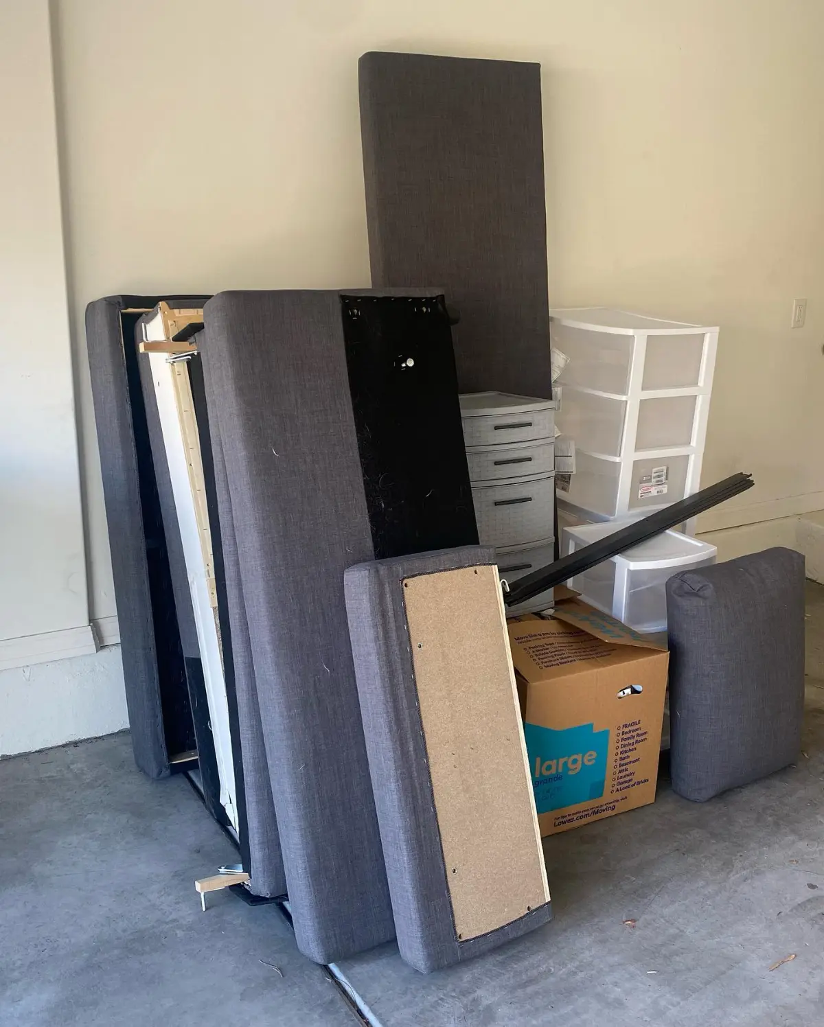 A mattress, box spring, upholstered headboard, drawer towers and boxes stacked in a Chandler garage bay