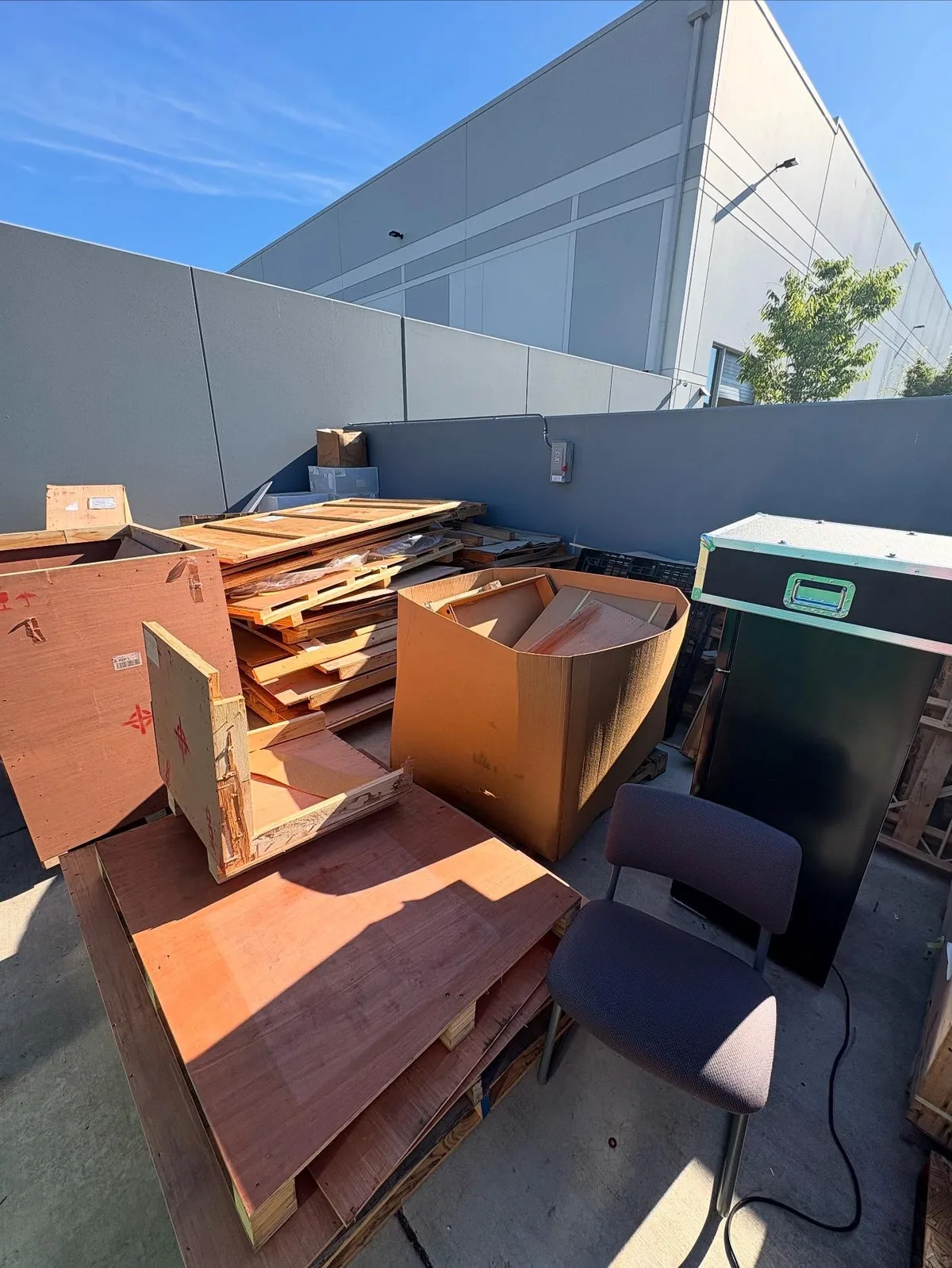 Wood panels, boxes, furniture pieces, and commercial debris in a Chandler outdoor storage area before junk removal