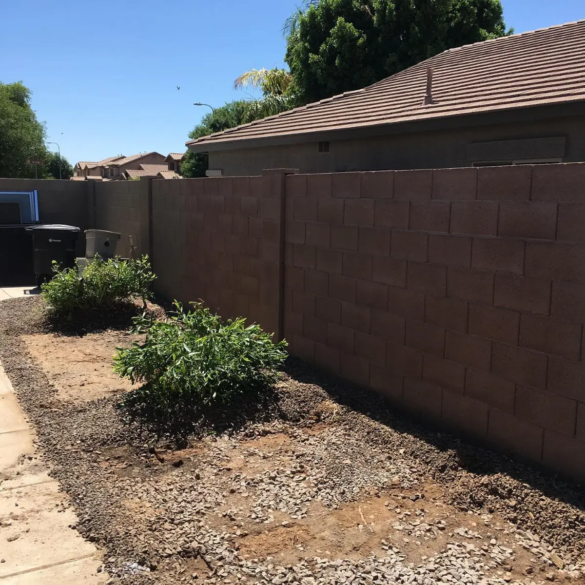 The same Chandler side yard with all three sheds gone, cleared to open gravel and dirt along the block wall