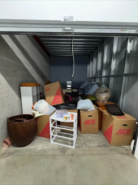 An indoor storage unit in Chandler with boxes, a mattress, a wicker basket, plastic drawers and bagged items