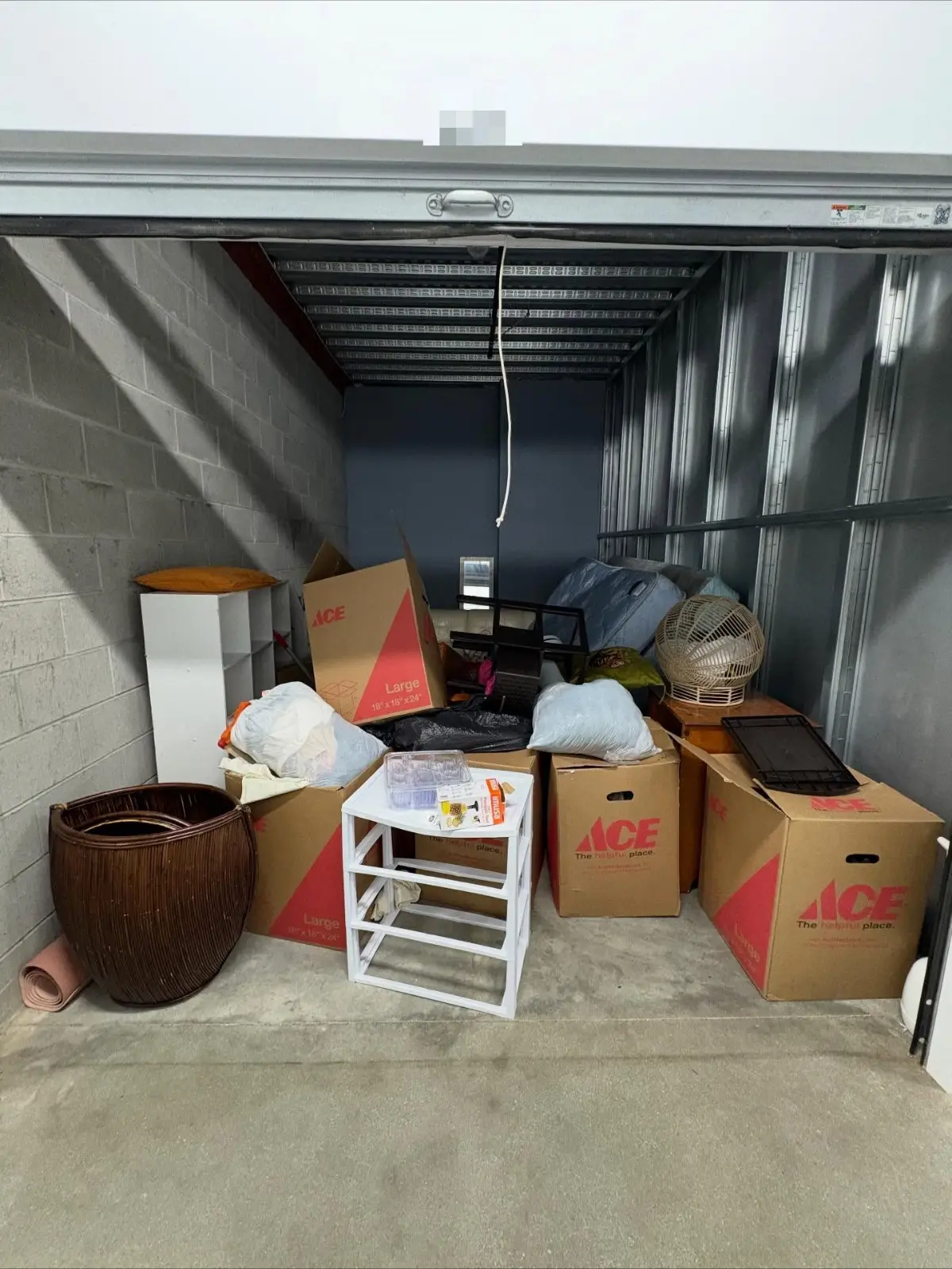 An indoor storage unit in Chandler with boxes, a mattress, a wicker basket, plastic drawers and bagged items