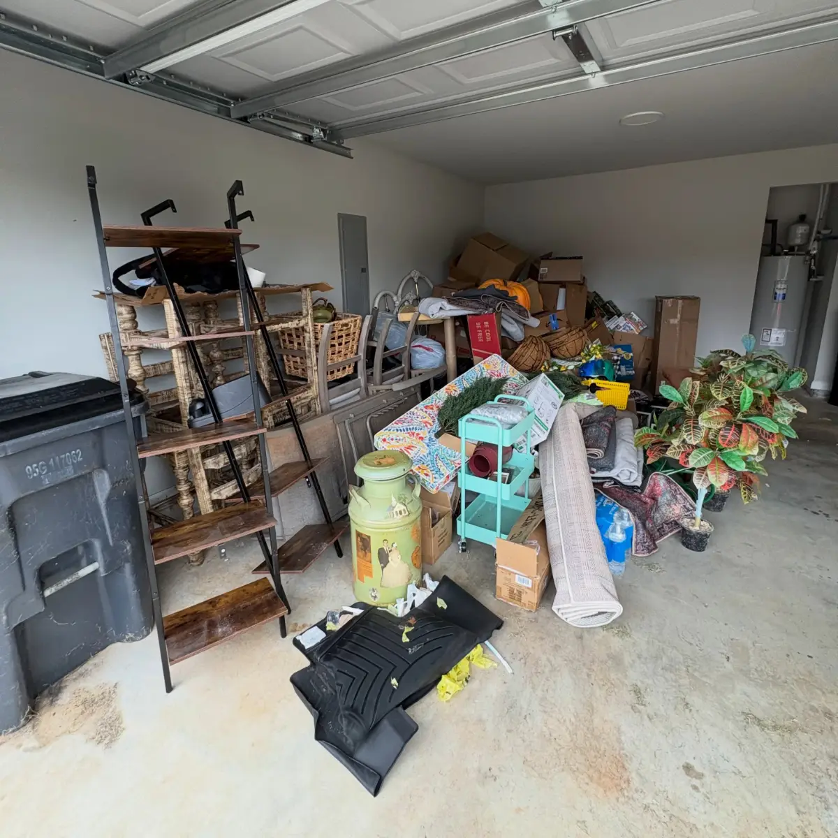 Gilbert garage with a ladder bookshelf, carved console, chairs, rolled rugs, boxes and decor across the floor