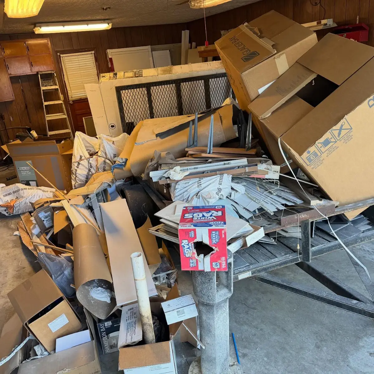 Glendale garage filled with boxes, trim, bagged debris and cabinet pieces piled over a small trailer