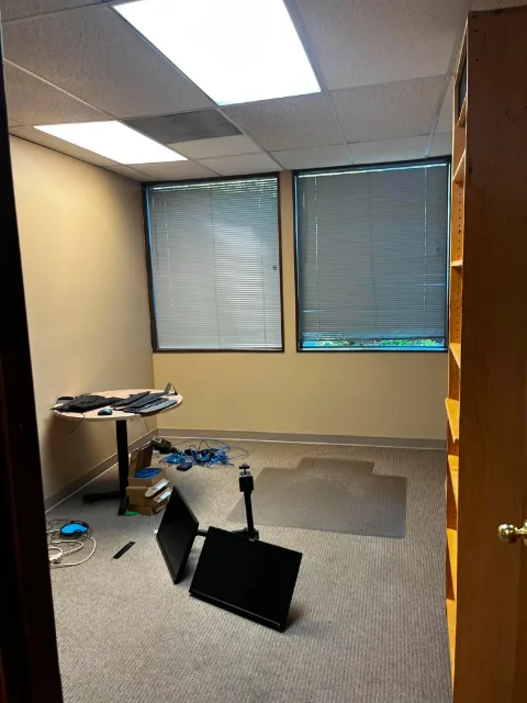 A Mesa office with a round table of keyboards and monitors, more monitors face down on the floor, cabling and boxes