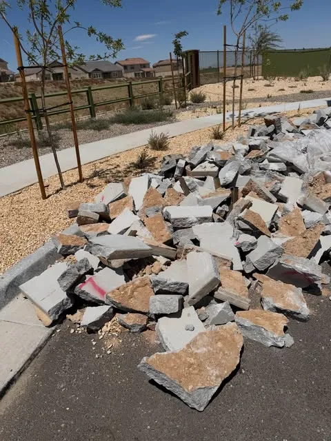 Broken concrete and flagstone slabs piled on the curb beside a new Mesa sidewalk before Haulo hauled them away