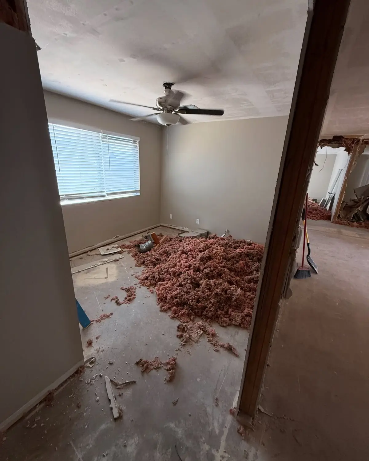Bedroom in a Mesa home mid-remodel with a mound of blown insulation and trim across the slab