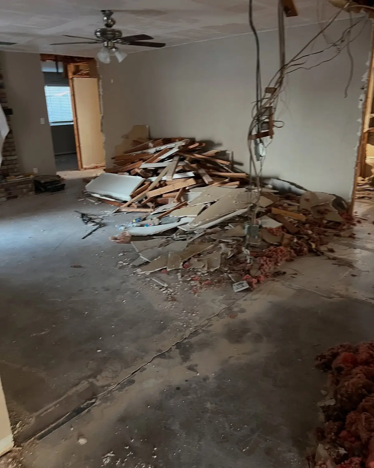 Living room of the same Mesa remodel with a pile of framing lumber, drywall and insulation on the slab