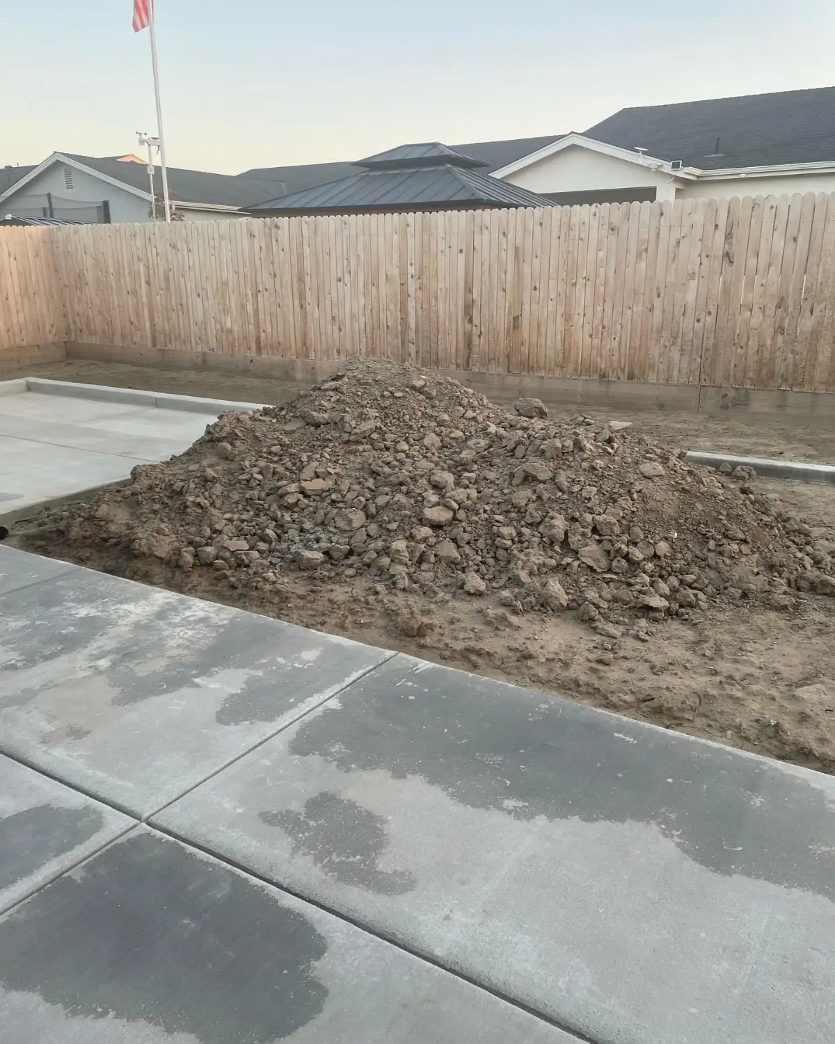 Large mound of excavated dirt beside a concrete slab and block wall at a Mesa property