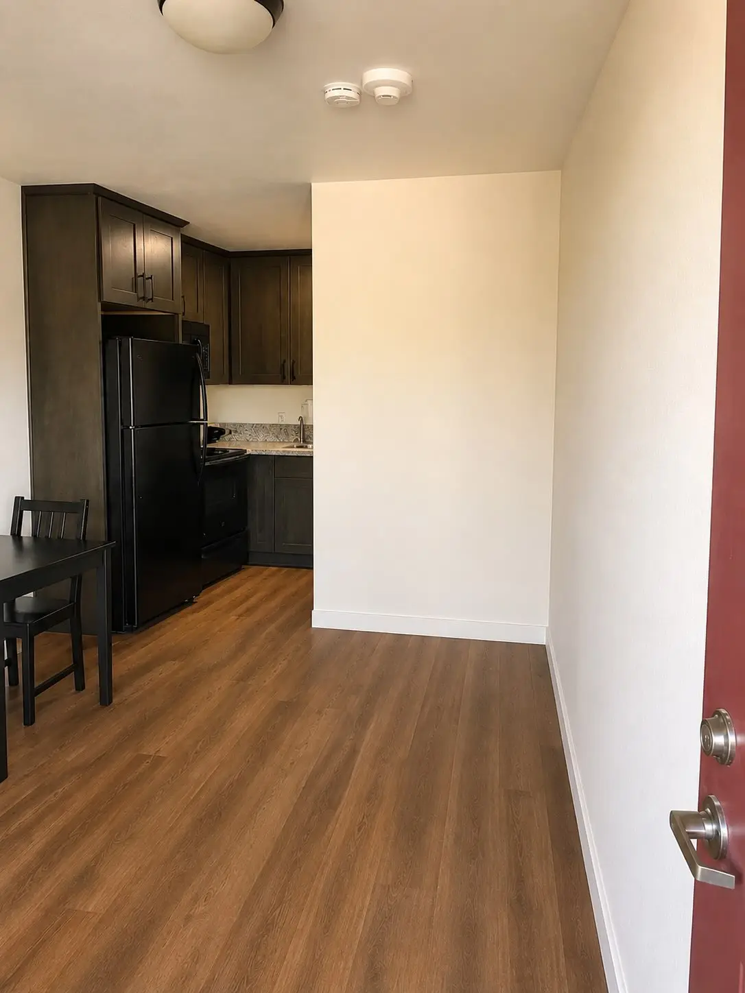 The same Mesa apartment kitchen and entry cleared to the floor; the unit's table, chair and refrigerator remain