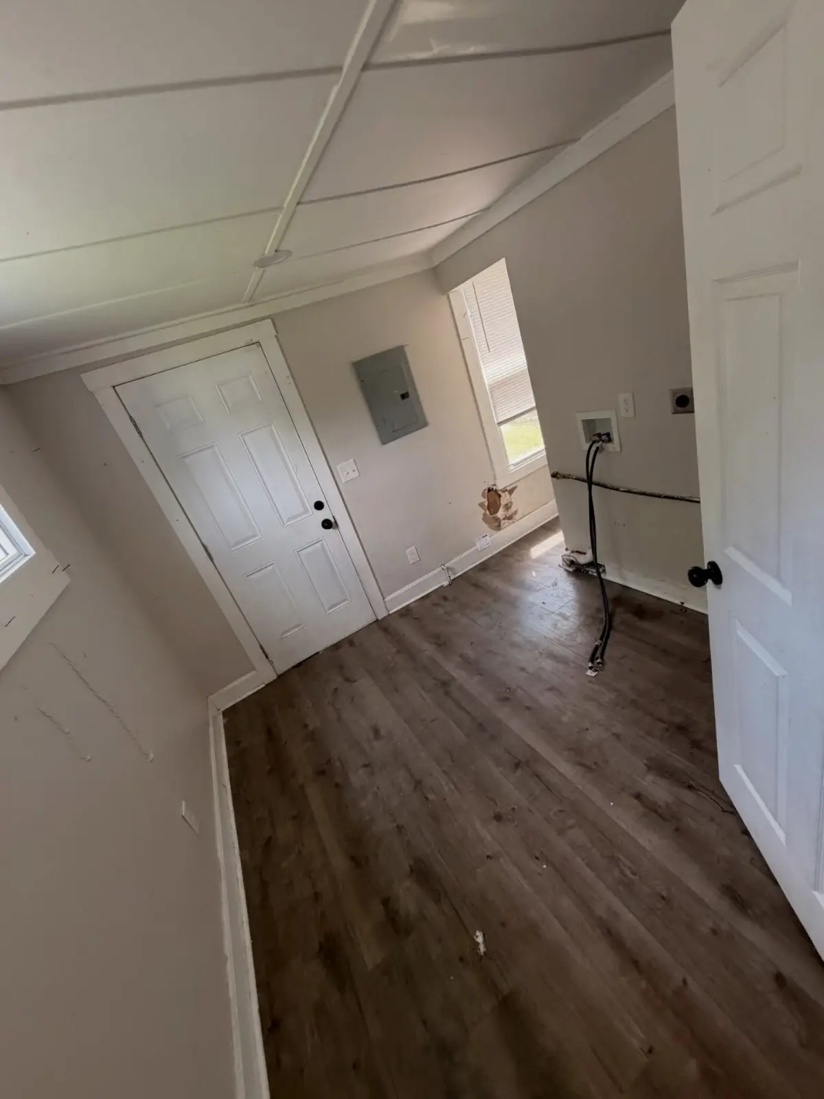 The same Mesa entry and laundry area cleared, with the floor emptied and the washer hookups exposed