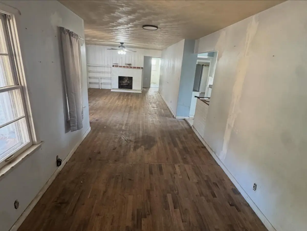 The same Mesa living room cleared to the bare hardwood floor with the fireplace and built-in shelves open