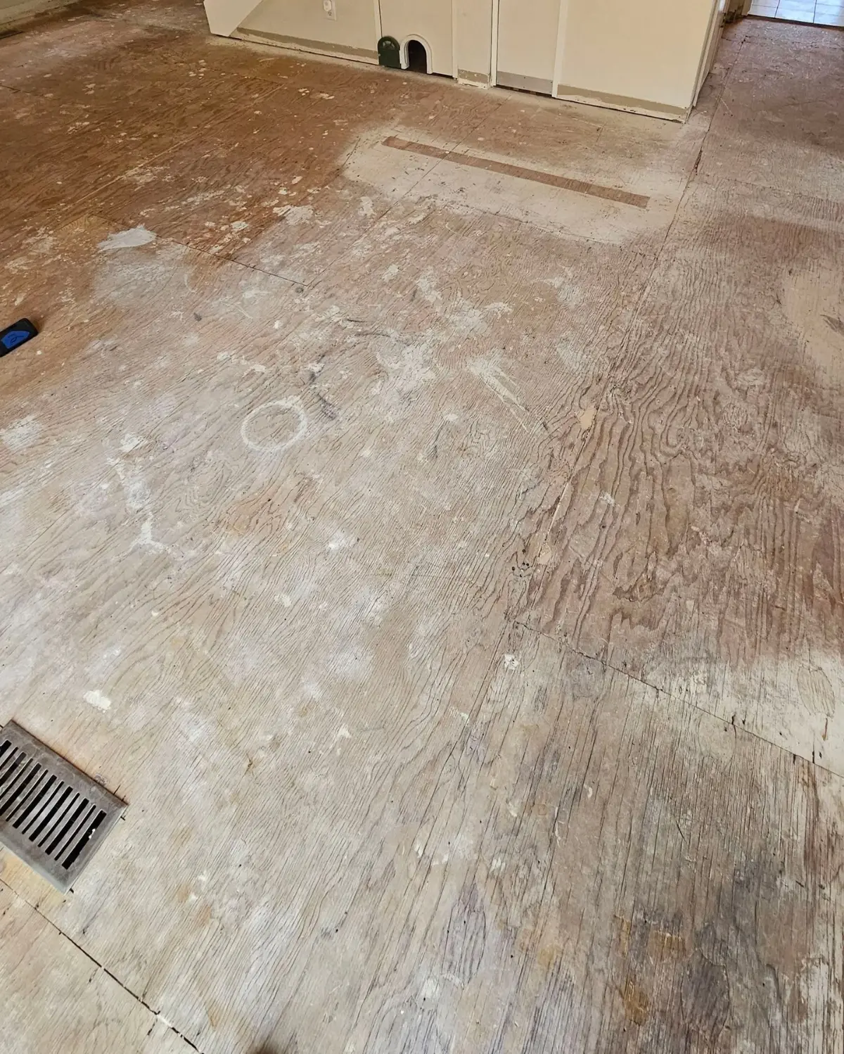 The same Mesa floor with the tile broken out and the plywood subfloor exposed
