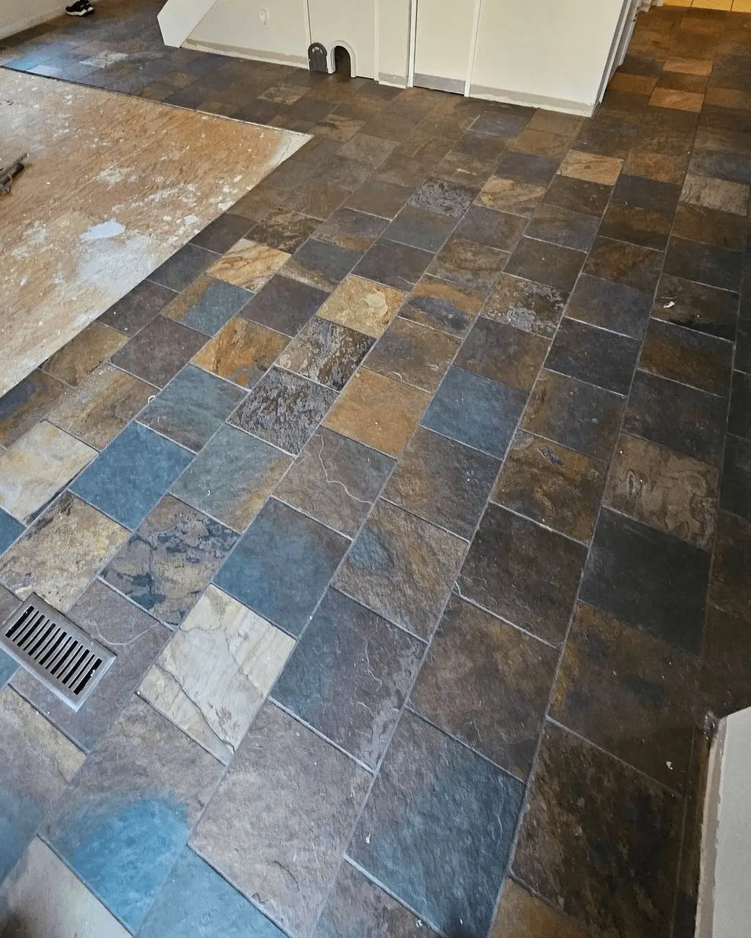 A slate tile floor running through to the cabinet toe-kicks in a Mesa home before demolition