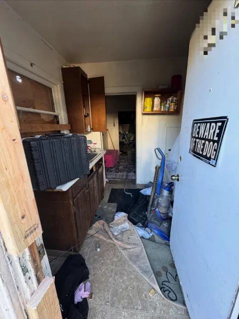 A narrow galley kitchen in a Mesa rental unit with a hard case on the counter, a vacuum, a rug and bagged items on the floor