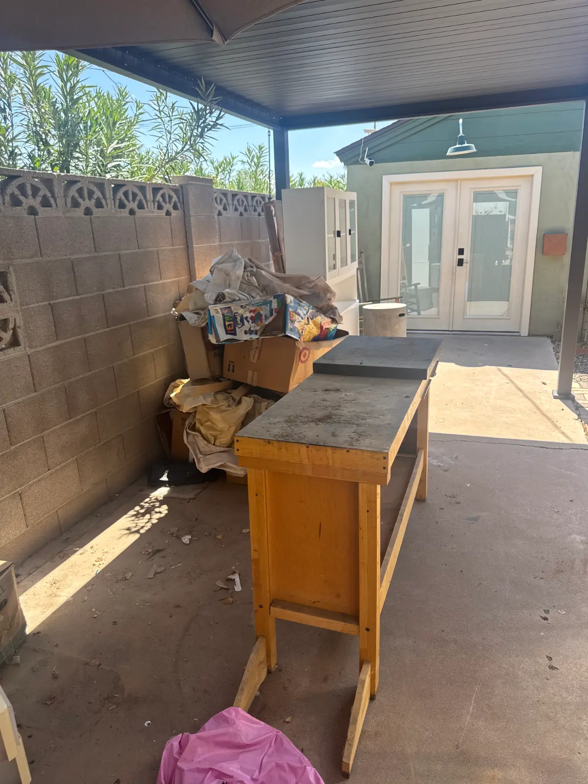 A wooden workbench, boxes and drop cloths crowded into the corner of a covered Peoria patio