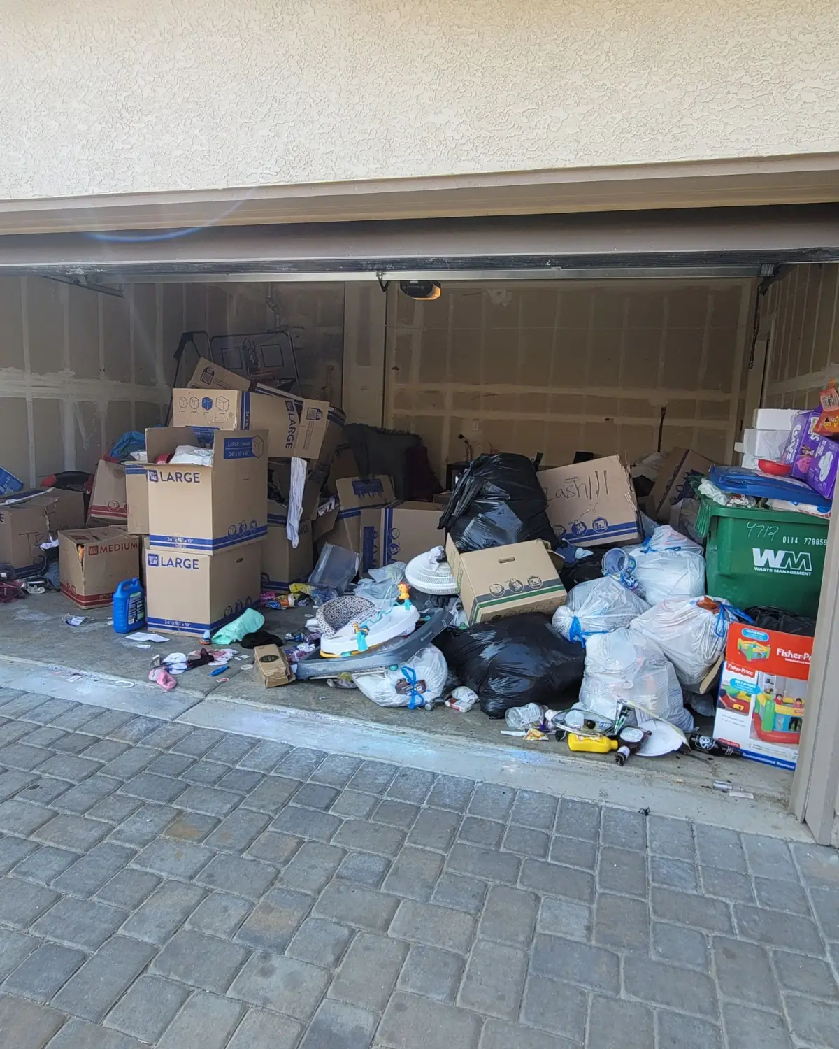 A Phoenix garage packed to the door with moving boxes, bagged trash and baby gear