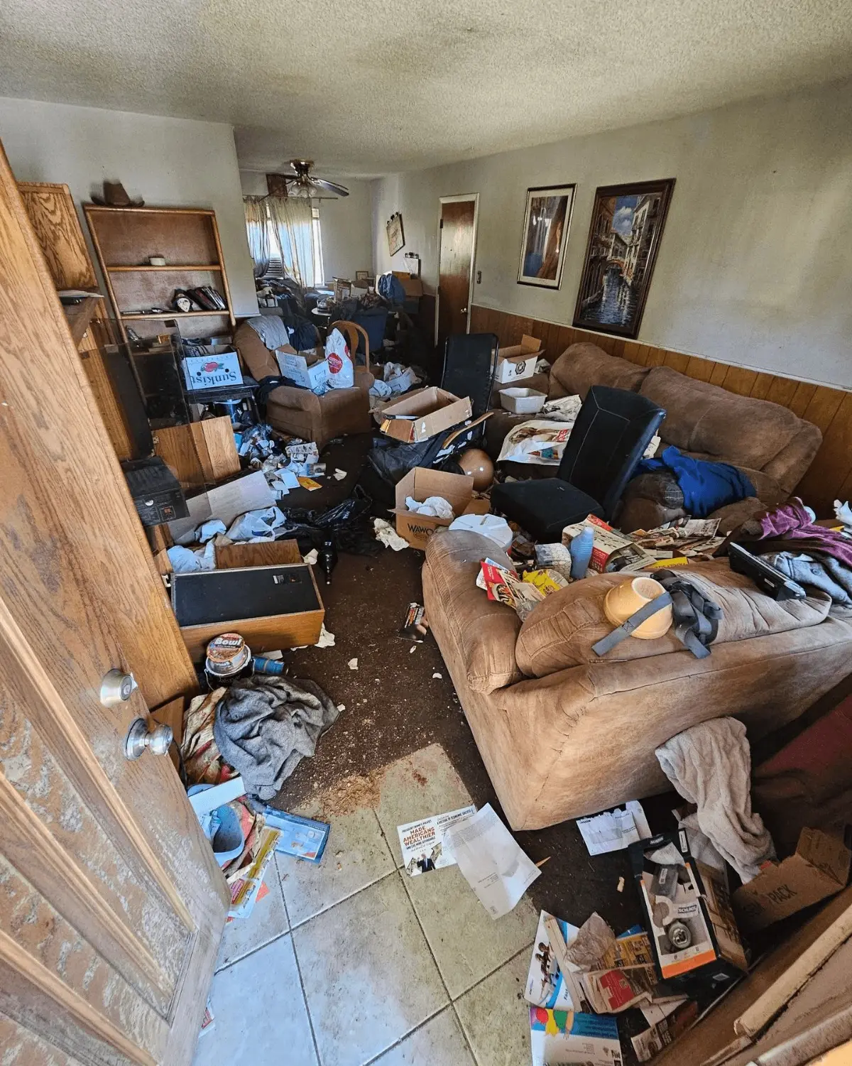 A Phoenix living room filled with sofas, boxes, bagged trash and loose contents across the floor