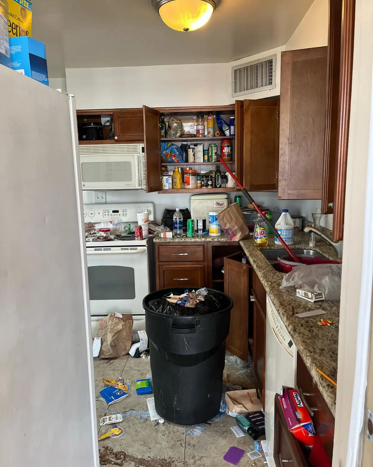A Scottsdale kitchen with a trash can, food and open cabinets full of contents on the counters
