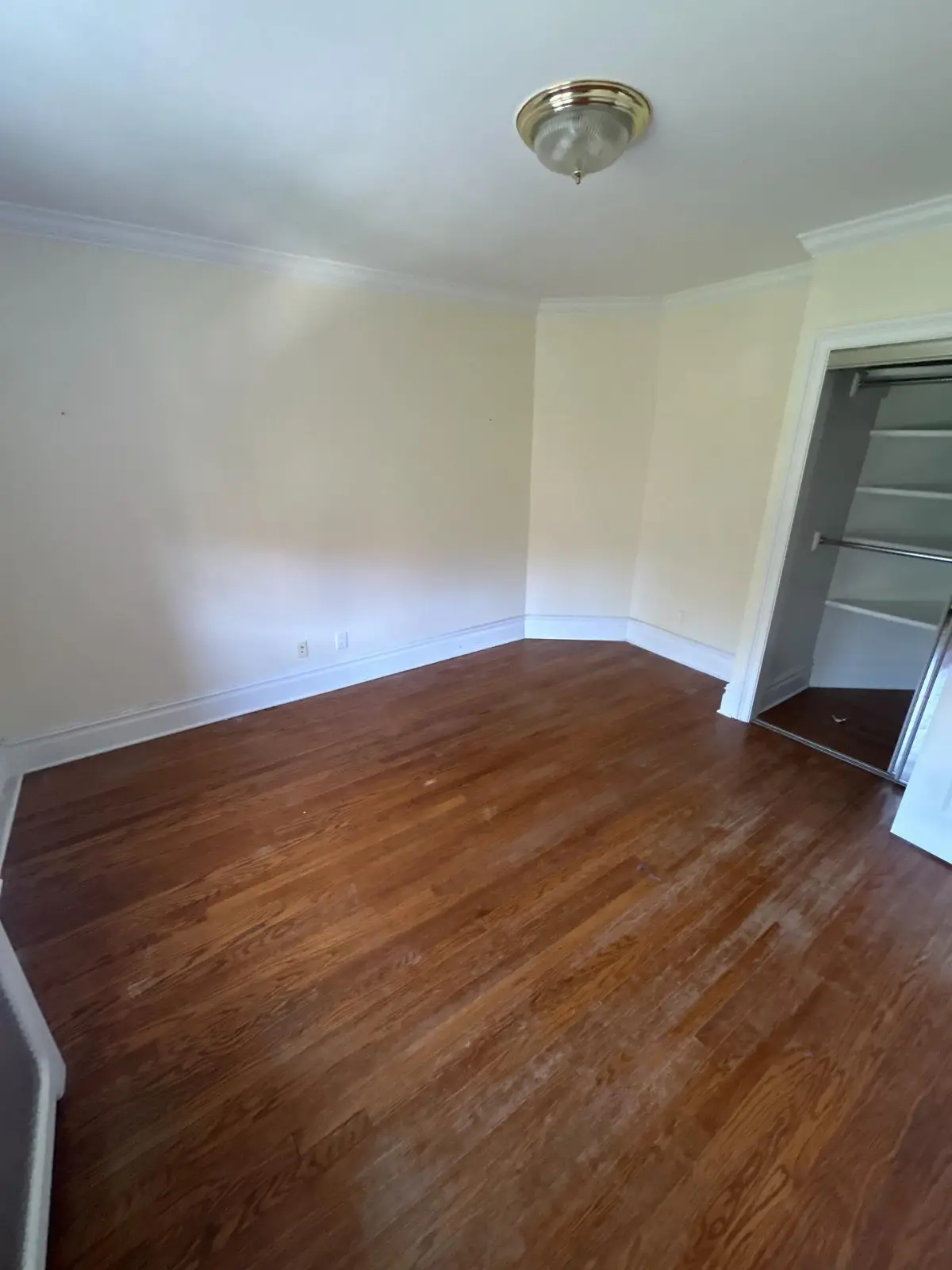 The same Scottsdale bedroom emptied to the hardwood floor, with the mirrored closet door visible