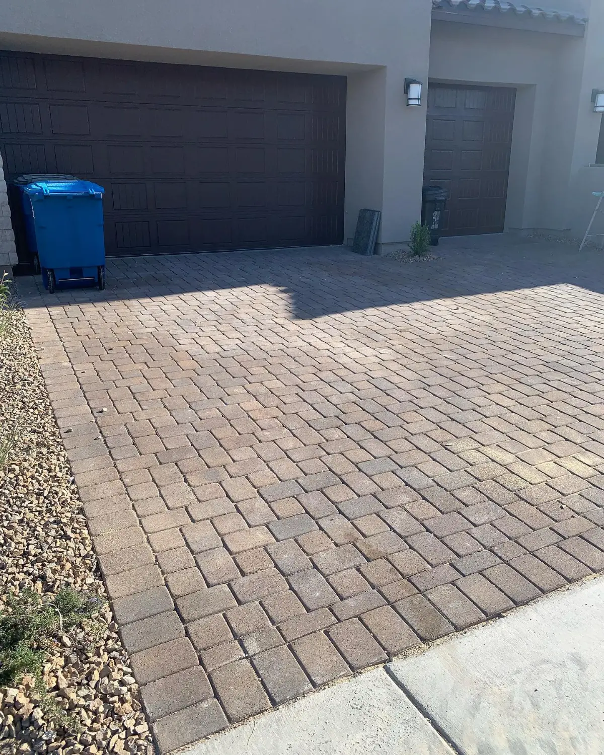 The same Scottsdale paver driveway clear, with a blue recycling bin beside the garage