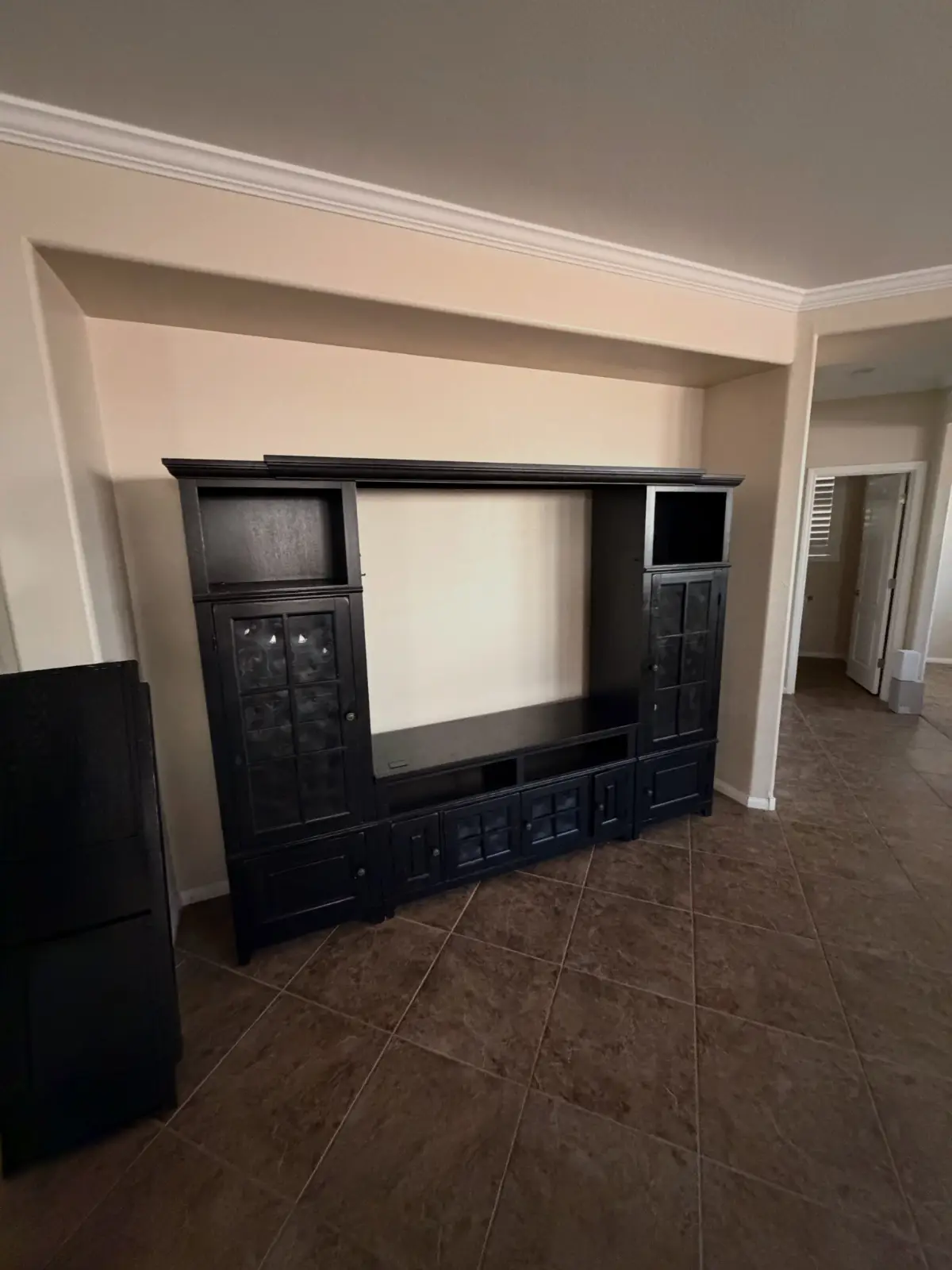 A large dark entertainment center filling a built-in alcove on tile flooring in a Tempe home